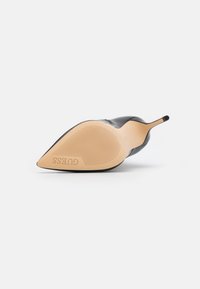 Czarny but na wysokim obcasie z wydłużonym noskiem, gładkim wykończeniem i gumową podeszwą z rowkami. Wytłoczone logo "GUESS" na podeszwie.