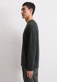 Dunkelgrauer, langärmeliger Pullover aus weichem Stoff, mit Rundhalsausschnitt und lockerer Passform, kombiniert mit strukturierten grünen Cordhosen.