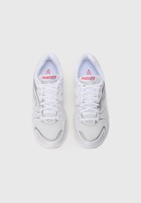 Scarpe sportive bianche con tomaia in rete, dettagli argentati e rifiniture grigie. Lacci a contrasto e colletto imbottito. Logo del brand rosso sulla linguetta.