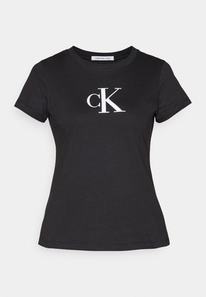 T-shirt de algodão preto com um logótipo branco "CK" no lado superior esquerdo do peito. Mangas curtas e decote redondo com um corte padrão.