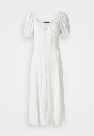 White dress with a textured fabric, puff sleeves, square neckline, and a front tying detail at the bust. Falls to the mid-calf.