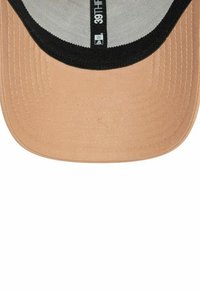 Gorra de béisbol de color tostado con visera negra, con una superficie texturizada y costuras visibles en el borde de la visera, etiqueta de la marca en el interior.