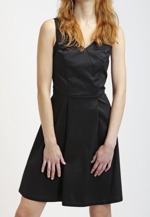 Musta hihaton mekko, jossa on vartaloa mukaileva yläosa ja levenevä helma. Valmistettu sileästä, hieman kiiltävästä kankaasta. Mekossa on V-kaula-aukko eikä näkyviä koristuksia.
