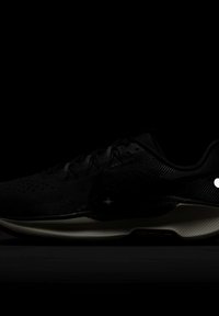 Zapatilla de correr negra con parte superior de malla texturizada, sistema de cordones prominente, suela acolchada y acentos naranjas con la marca "NIKE TRAIL".