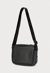 Μαύρο συνθετικό τσαντάκι crossbody με λεία υφή, ορθογώνιο σχήμα, ρυθμιζόμενο λουρί και κλείσιμο με φερμουάρ· διαθέτει λουρί με λογότυπο.