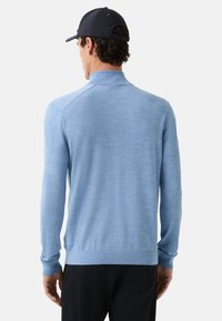 Himmelblauer, langärmeliger Pullover mit hohem Kragen, gerippten Bündchen und geradem Saum. Wolltextur, minimalistisches Design ohne sichtbare Muster.