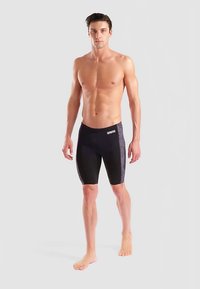 Svarta badshorts med en figursydd design, med en strukturerad grå sidopanel och en logotyp framtill. Slät, stretchig tyg.