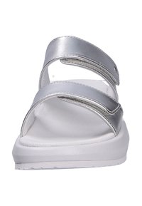 Sandalias plateadas con diseño de dos correas ajustables, hechas de material suave, con una suela blanca y ligera y detalles de costura mínimos.