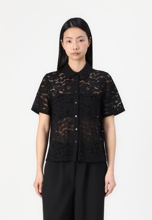 Camiseta negra de encaje de manga corta con cuello, que presenta patrones florales, cierre de botones en la parte delantera y una textura semitransparente.
