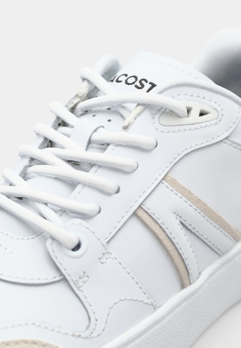 Weiße Leder-Sneaker mit glatter Oberfläche, beigen Akzenten, weißen Schnürsenkeln und einer strukturierten Sohle. Lacoste-Logo auf der Zunge.