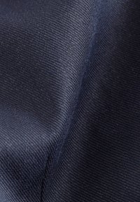 Tissu bleu marine foncé avec une texture lisse, présentant un motif de tissage fin. Le matériau est léger, drapé doucement en plis.