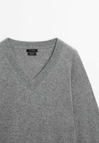 Gray v-neck sweater made of soft knit material. Features ribbed cuffs and hem, with a smooth texture and minimal stitching details.