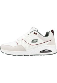 Baskets blanches de sport avec des accents en suède gris, design perforé, présentant un coussin d'air visible et une semelle grise. Logo avec des détails en vert et rouge.