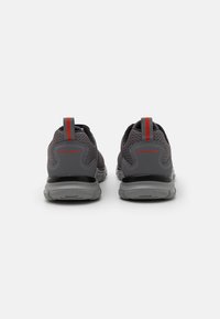Gray mesh athletic shoes with a textured pattern, accented by a red pull tab. Features a cushioned sole for comfort and support.