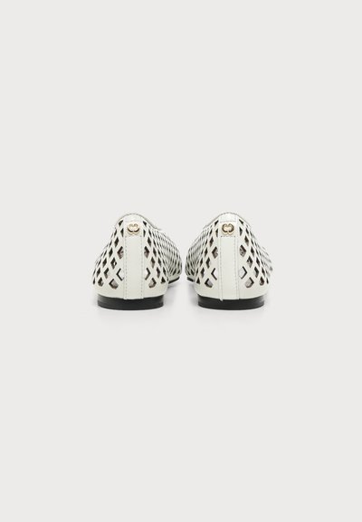 Paire de chaussures plates blanches avec des découpes en forme de losange et un petit logo doré au talon, vues de dos sur un fond uni.