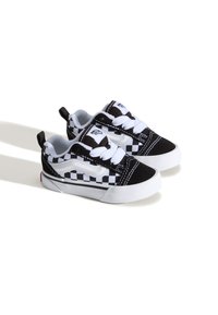 Mustat ja valkoiset ruudulliset kangaskengät valkoisilla nauhoilla, pehmustettu varsi ja kumipohja, jossa on pieni punainen yksityiskohta kannassa.