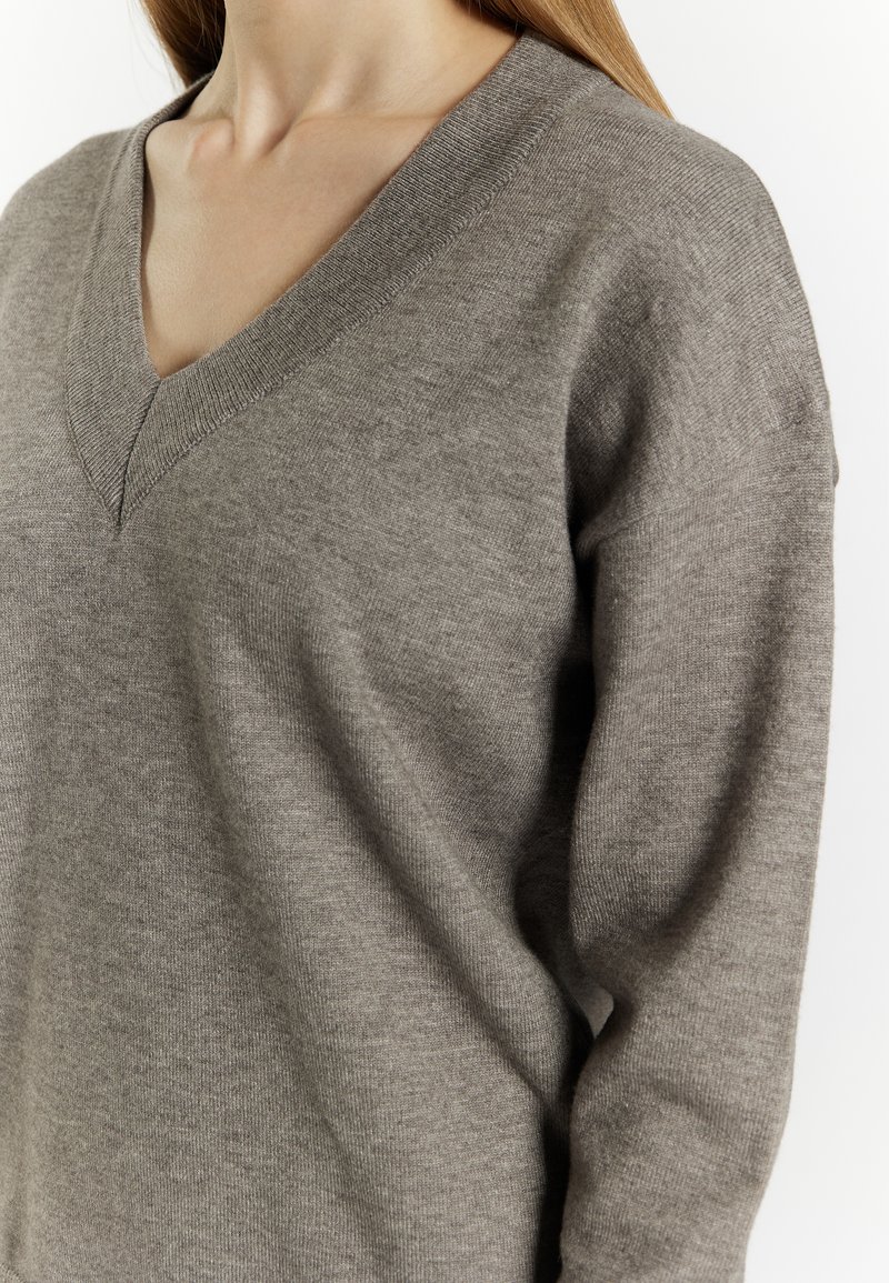 V-Ausschnitt Pullover aus weichem, hellgrauem Stoff. Bietet eine lockere Passform mit glatter Textur und gerippten Details am Kragen und den Ärmeln.