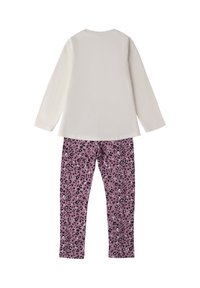 Witte top met lange mouwen, gecombineerd met paarse luipaardprint leggings, tegen een effen witte achtergrond, gepresenteerd vanuit de achterkant.