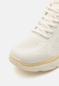Könnyű fehér sneakers a texturált h�álós felsőrésszel, megerősített orral és diszkrét bézs akcentussal a talpon és a galléron.