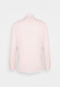 Vaaleanpunainen pellavapaita, jossa pitkät hihat, klassinen kaulus ja sivuhalkiot. Paidassa on kalvosinnapit ja sileä, kudottu rakenne.