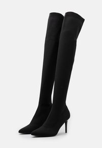 Černé kozačky nad kolena vyrobené z elastického materiálu, s špičatou špičkou a jehlovým podpatkem; žebrovaný vršek pro bezpečné nošení; elegantní design.
