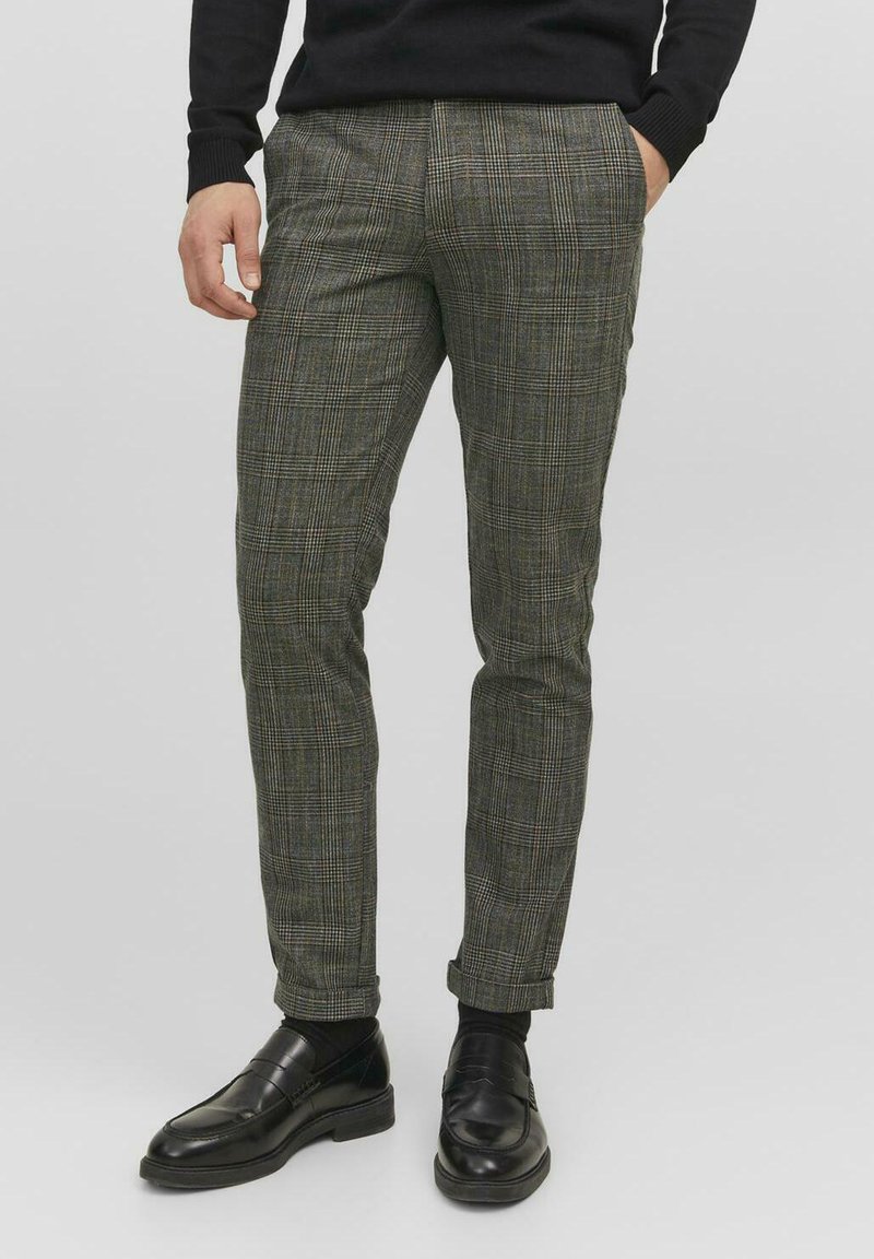 Pantalons à carreaux verts avec une coupe slim, avec une texture subtile. Associés à des mocassins en cuir noir.
