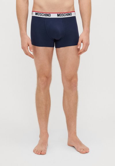 Μπλε βαμβακερά μποξεράκια με φαρδύ λευκό ελαστικό ύφασμα που έχει κόκκινες λεπτομέρειες και το λογότυπο "Moschino", εφαρμοστό σχέδιο με απαλό άγγιγμα.