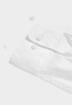 White long-sleeve shirt cuff with two button closures, featuring a smooth texture and crisp stitched detailing. Buttons are round and plastic.