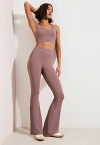 Set de bustier sport roz prăfuit și colanți evazați, confecționat din material elastic, cu textură netedă și detalii fără cusături.