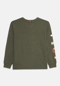 Donkergroene lange mouwen shirt met geribbelde manchetten en vier aparte patches langs de rechtermouw, weergegeven vanuit de rug.