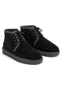 Botas de tobillo de ante negro con una superficie texturizada, detalles en gris, cordones redondos y un forro acolchado, que cuentan con una suela de goma duradera.