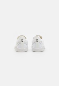 Hvide sneakers med en strikket overdel, tekstureret gummisål og logo detaljer på hælen. Udstyret med trækstropper for nem påtagning.