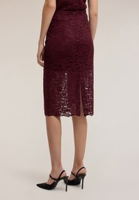 Burgundinpunainen pitsinen kynähame kukkakuviolla, keskivartalon mittainen, jossa takana halkio. Yhdistetty mustiin korkokenkiin.