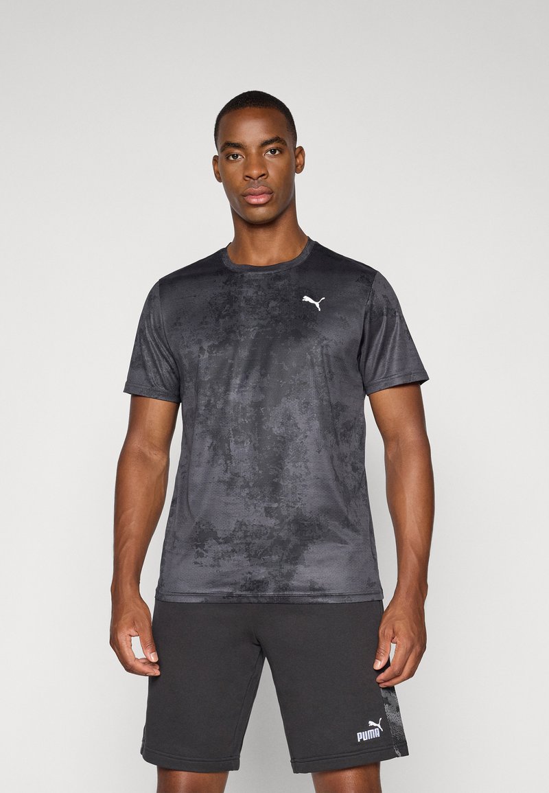Svart treningstopp med teksturert mønster, korte ermer og hvit Puma-logo på brystet, kombinert med svarte shorts med sidemotiv.