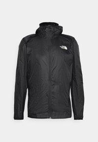 Veste légère noire à fermeture éclair avec capuche et logo The North Face sur la poitrine, présentée sur un fond uni.