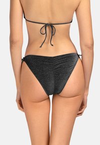 Czarne majtki bikini o błyszczącej fakturze, z wysokim krojem i regulowanymi bocznymi wiązaniami, zdobione marszczeniem z tyłu dla dodatkowego efektu.