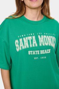 Zelené bavlněné tričko s kulatým výstřihem. Text obsahuje "SANTA MONICA STATE BEACH" v bílé a krémové barvě. Volný střih.