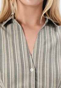 Gestreifte button-up Hemd in Grau und Creme. Mit Kragen, Knopfleiste und weichem Leinenstoff. Vertikale Streifen in unterschiedlichen Breiten.