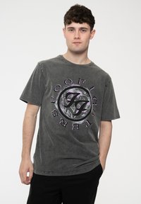 Grey crewneck t-shirt made of cotton, featuring a circular graphic design in black and purple with the text "FOO FIGHTERS." Short sleeves.