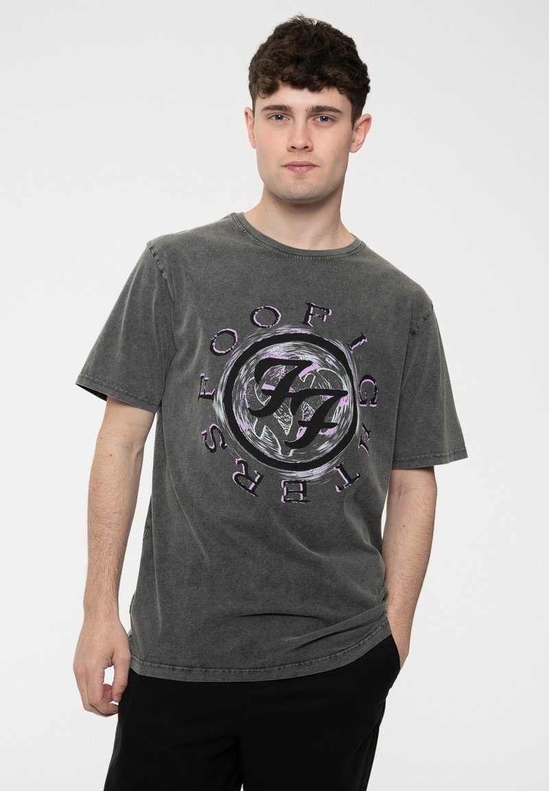 Grey crewneck t-shirt made of cotton, featuring a circular graphic design in black and purple with the text "FOO FIGHTERS." Short sleeves.