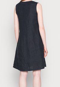 Robe sans manches, longueur genou, en lin bleu marine foncé. Elle présente un col rond et une silhouette légèrement évasée, avec un design épuré et simple.