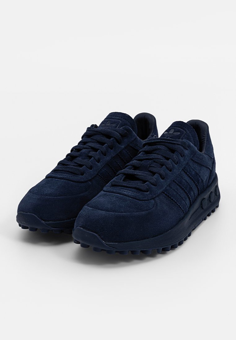 Baskets en daim bleu marine avec une surface texturée, présentant des orteils ronds, un design à lacets, des accents rayés et une semelle rembourrée.