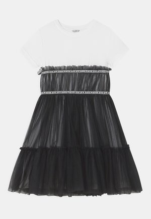 Vestido de tul negro con parte superior blanca, con cintura fruncida, banda elástica contrastante con texto y falda de volantes en capas.