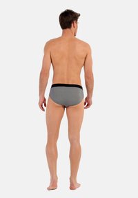 Heren zwemslip met een grijs stippenpatroon, zwarte tailleband, elastisch materiaal en een aansluitende pasvorm, weergegeven vanuit de achterkant.