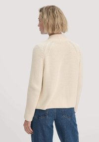 Cremefarbener Strickpullover mit gerippter Textur, runder Kragen, Raglanärmel und einer lockeren Passform im Rücken.