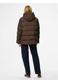 Brūns pūkains mētelis ar kapuci, ar quilted tekstūru un elastīgām aprocēm. Apvienots ar tumši ziliem taisniem džinsiem un melnām zābakiem.