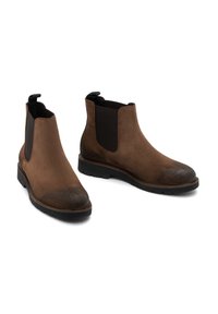 Botine Chelsea din suede maro, cu panouri elastice laterale negre, vârf rotunjit, bandă de fixare și talpă din cauciuc texturată.