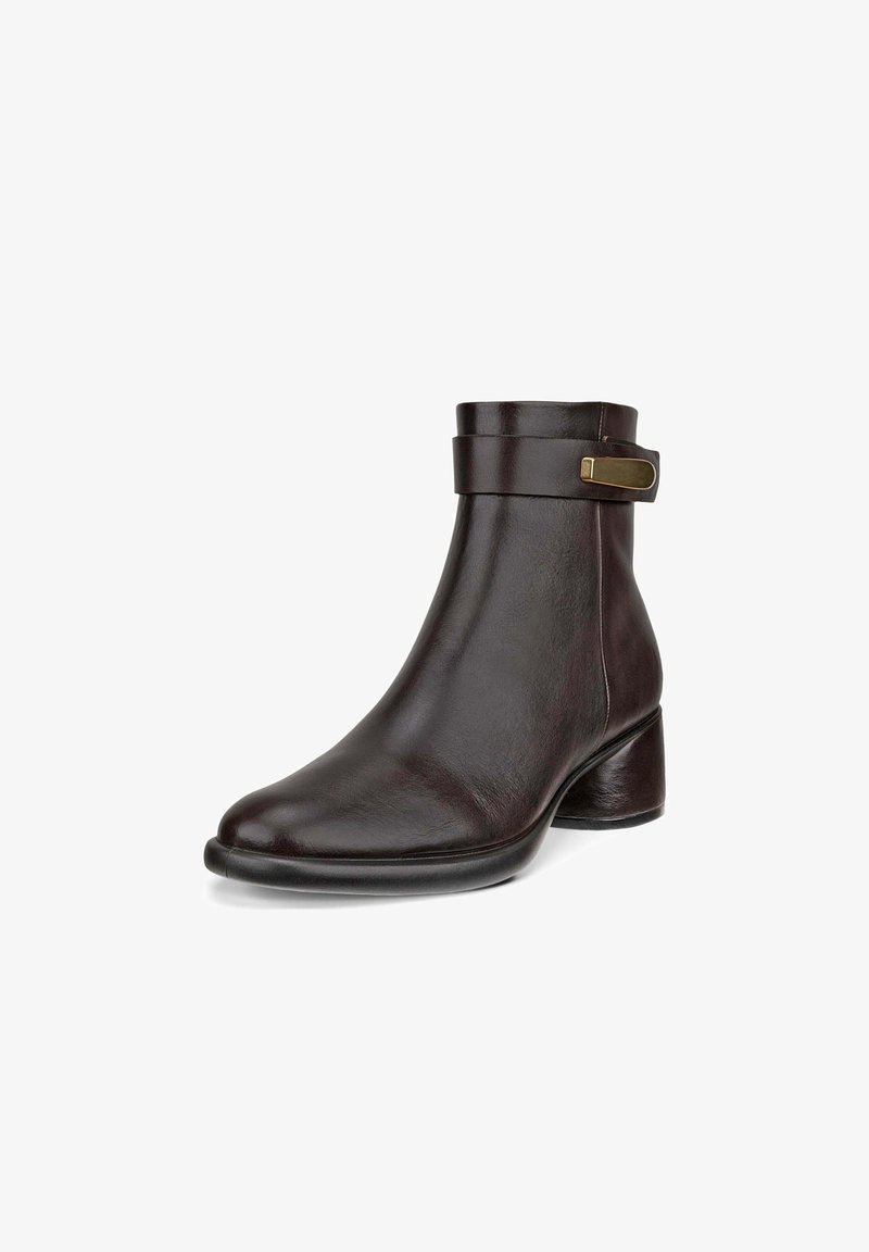 Bottine en cuir marron foncé avec un petit talon bloc et une bride décorative avec une boucle rectangulaire dorée près du haut.