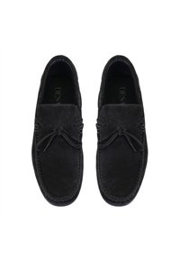 Schwarze Wildleder Slipper mit abgerundetem Zeh, dekorativem Bogen, kontrastierenden Nähten und flacher Sohle. Weiche Textur, lässiges Design.