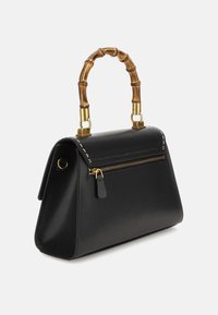 Sort læderhåndtaske med en struktureret form, bambushåndtag, guldhardware og en lynlåslomme på forsiden.